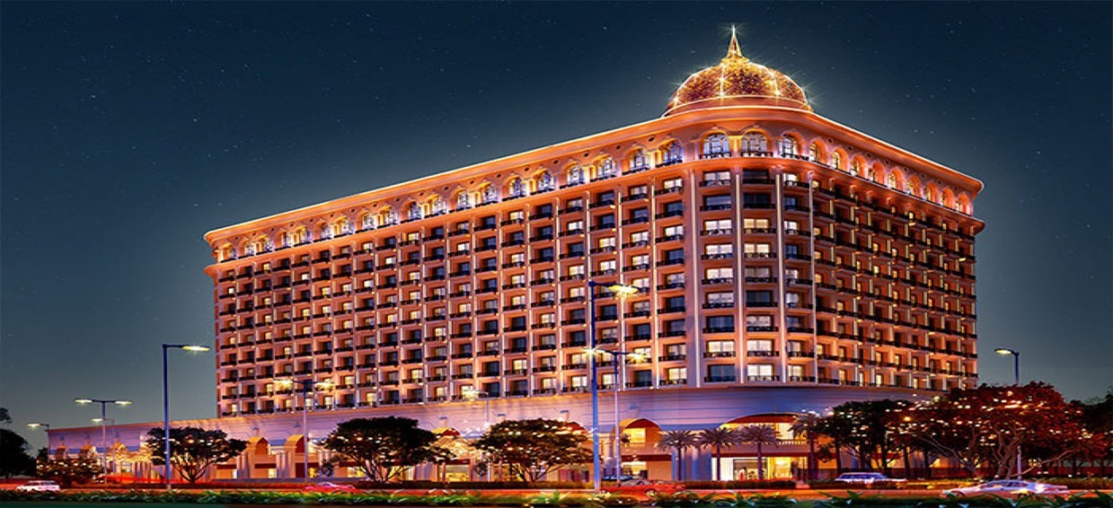Illuminated palace tower at night with golden dome and tree-lined street boulevard at Omaxe Bareilly